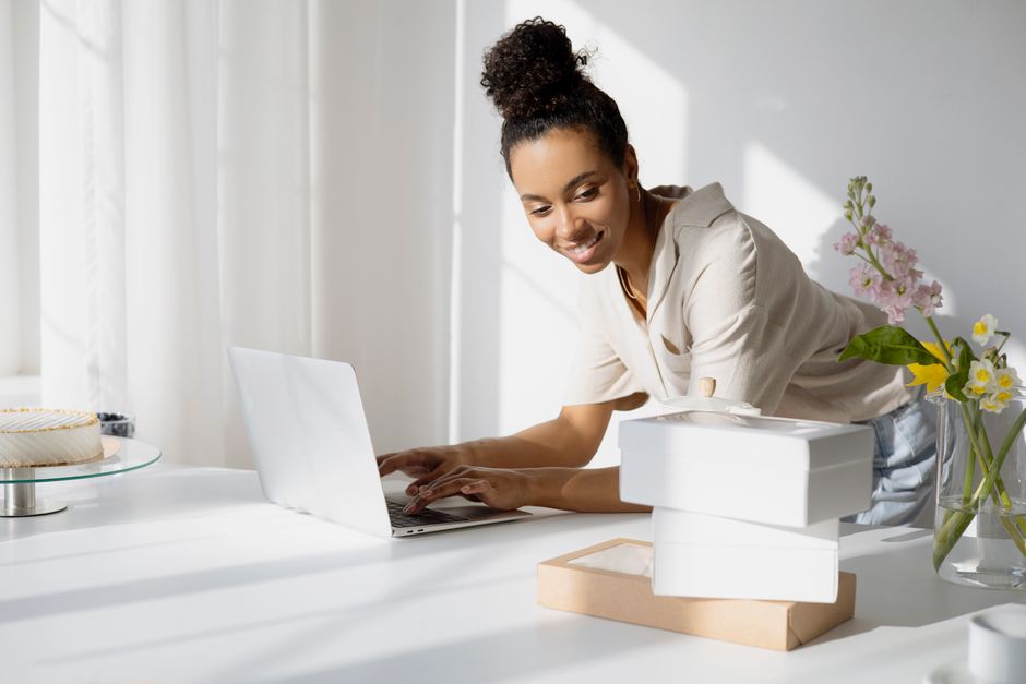 Emprendedora preparando su tienda online junto a cajas para pedidos