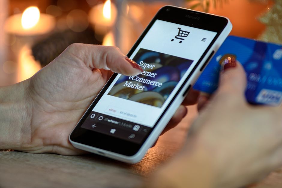 Persona revisando una compra desde su teléfono con la tarjeta a mano
